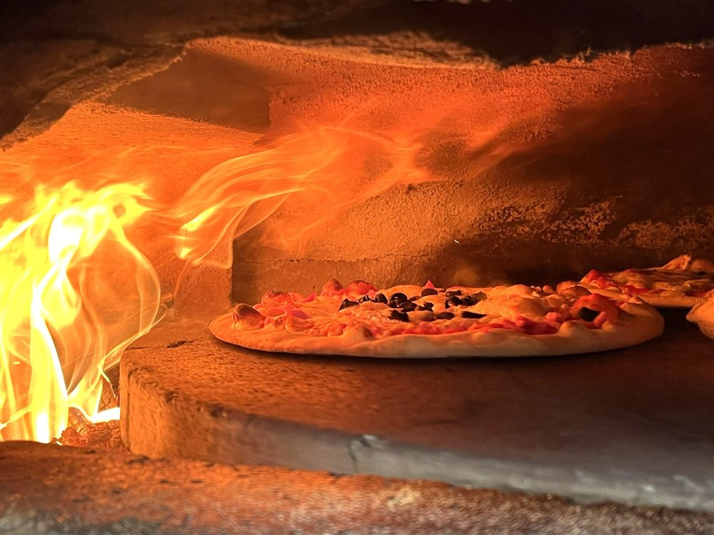 Pizzas cuite dans un four au feu de bois utilisé dans le food truck de Pizza Délice